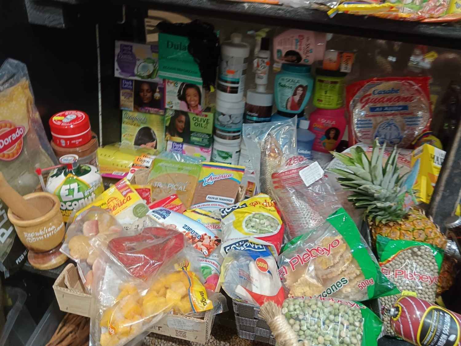 Estantería con alimentos envasados ​​y productos de belleza: arroz, salsas, productos para el cabello y una piña.