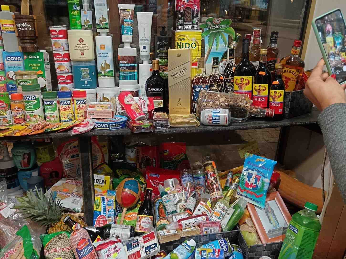 Una tienda abarrotada de productos envasados ​​y alcohol. Una persona toma una foto con su teléfono.