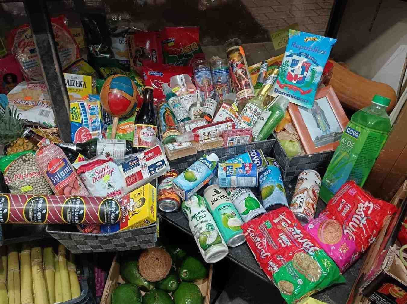 Surtido de alimentos envasados, incluidas latas, patatas fritas y bebidas, apilados en un estante.