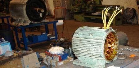 En un taller, dos estatores de motores eléctricos industriales reposan sobre bancos de trabajo; en uno de ellos se aprecian las bobinas de cobre y los cables amarillos.