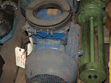 En un taller se encuentra un motor eléctrico industrial azul con un acoplamiento circular y un mecanismo de bombeo verde.