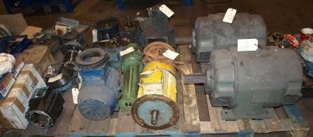 En un almacén, un palé de madera contiene una variedad de motores industriales, bombas y componentes mecánicos.