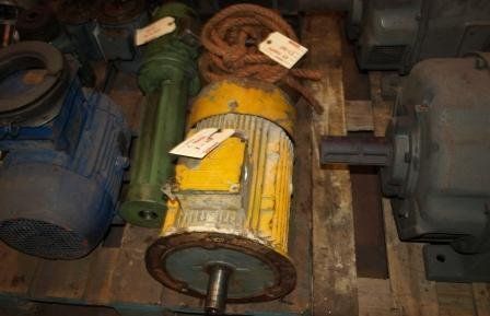 Varios motores eléctricos industriales y piezas de maquinaria reposan sobre un palé de madera en una zona de almacenamiento.