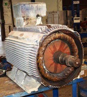 Un motor eléctrico industrial con su cubierta exterior retirada, dejando al descubierto el estator bobinado de cobre y el eje central del rotor.