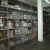 Estanterías repletas de cajas y suministros cuidadosamente organizados en un almacén o trastero con poca luz.