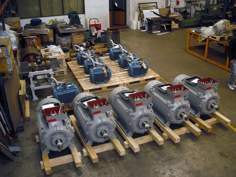 En un taller, varios motores eléctricos industriales están dispuestos sobre paletas de madera.