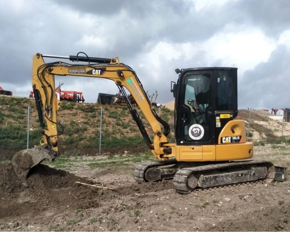 Excavadora Caterpillar amarilla cavando en tierra en un sitio de construcción.