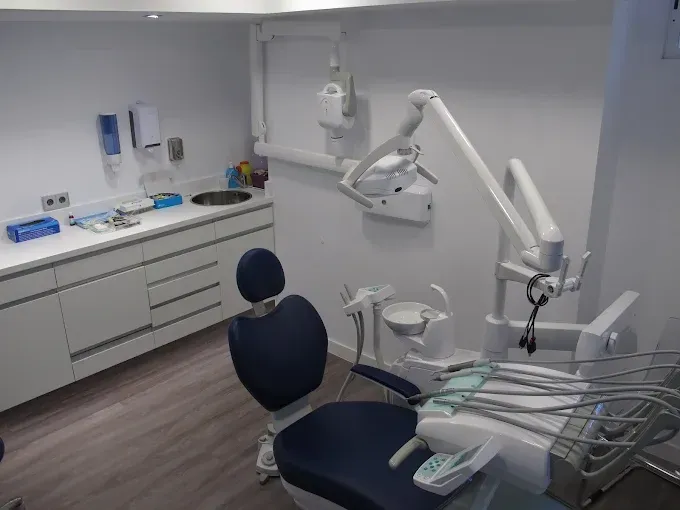 Un consultorio dental con un sillón dental y un lavabo.