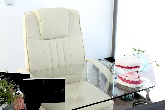 Una silla blanca está frente a una mesa de vidrio con un modelo de dientes sobre ella.