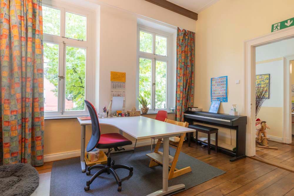 Flur mit gelben und weißen Wänden, Kunstwerken, kleinem Tisch mit Blumen, Spielzeug und Türöffnung.