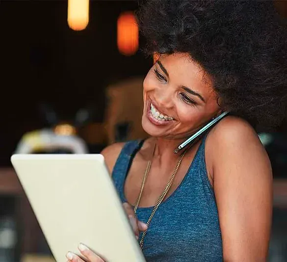 Una mujer está hablando por un teléfono celular mientras mira una tableta.