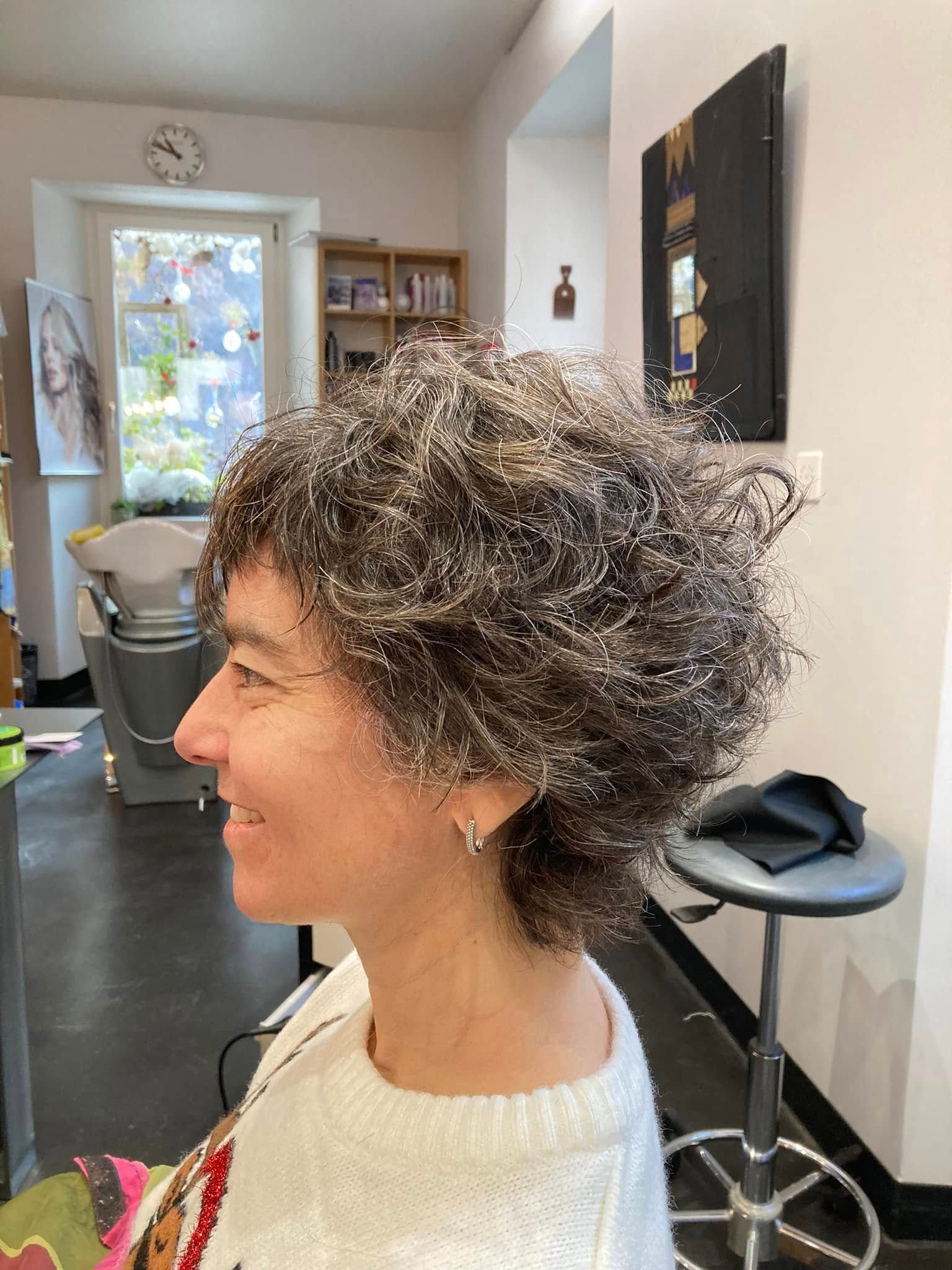 Vue de dos de cheveux bruns mi-longs aux pointes cuivrées, dans un espace d'exposition de coloration en salon.