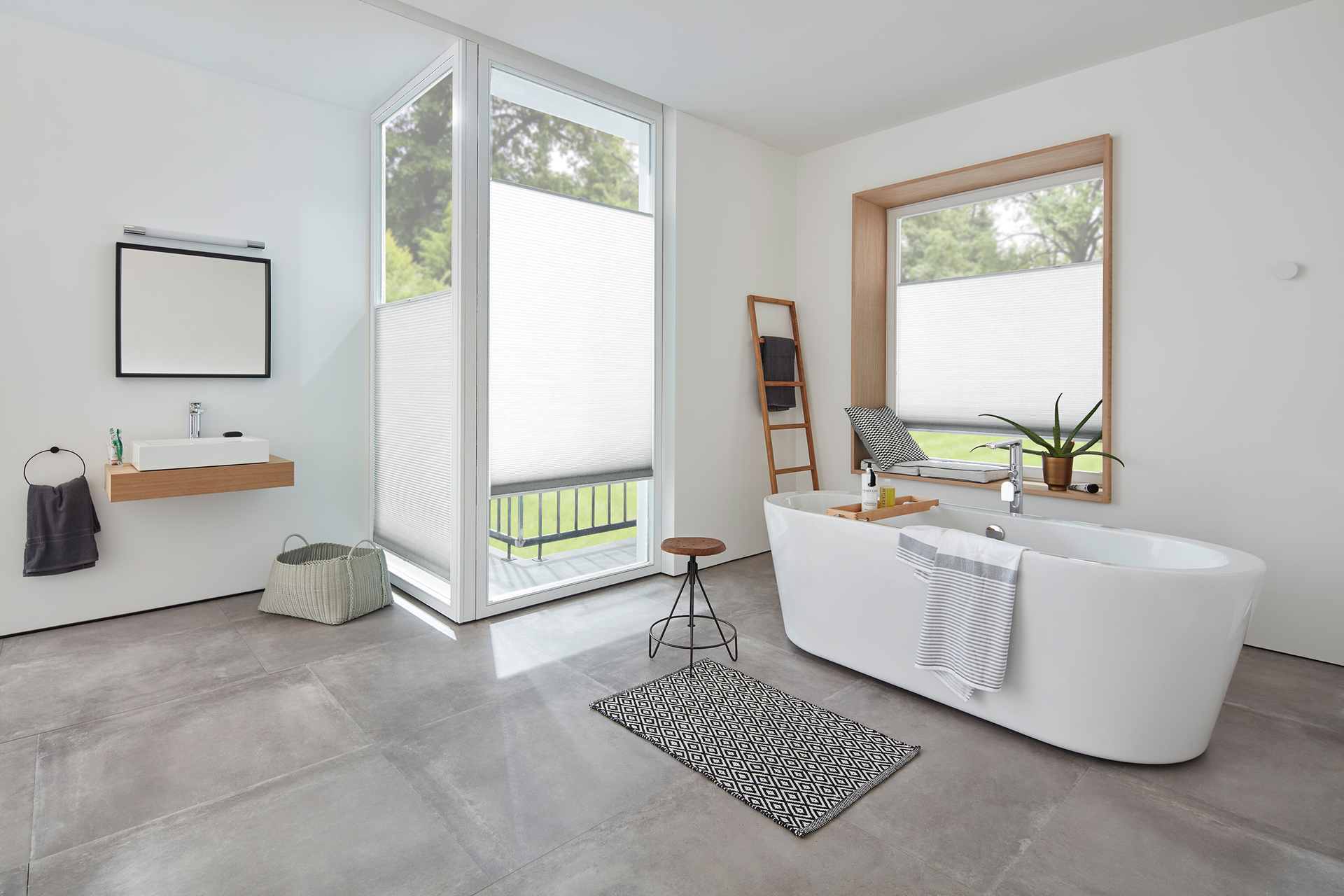 Modernes weißes Badezimmer mit freistehender Badewanne, Jalousien und Steinfliesenboden.