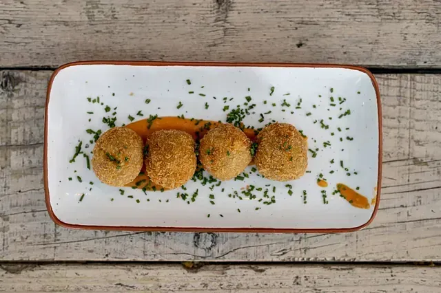 Un plato blanco con cuatro bolas de comida frita encima.