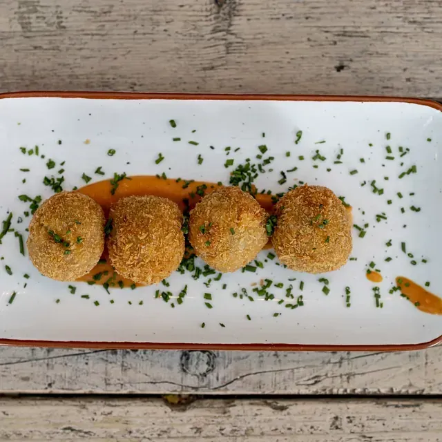 Un plato blanco con cuatro bolas de comida frita encima.