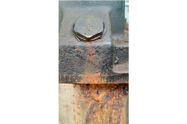 Un primer plano de un perno oxidado en un trozo de metal.