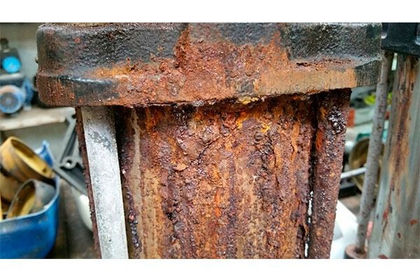 Un primer plano de un objeto de metal oxidado en un garaje.