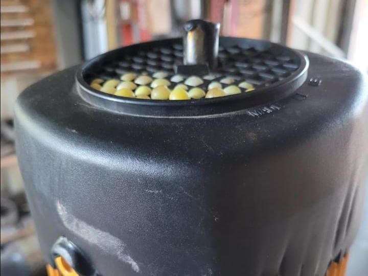 Un primer plano de un recipiente negro lleno de maíz.