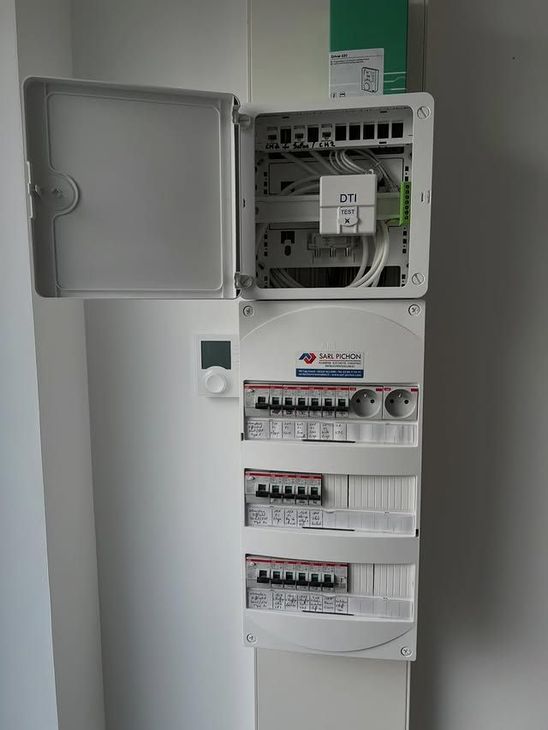 Armoire électrique murale blanche et boîtier de distribution réseau avec porte ouverte et disjoncteurs à l'intérieur.