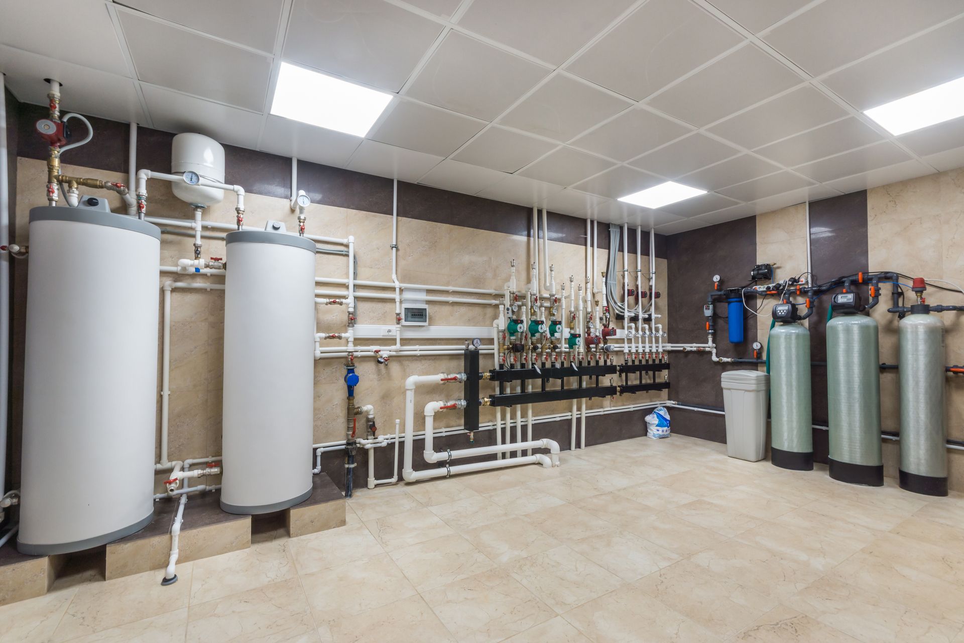 Salle de traitement des eaux industrielles avec de grands réservoirs blancs, des tuyaux et des cylindres métalliques sur un sol carrelé