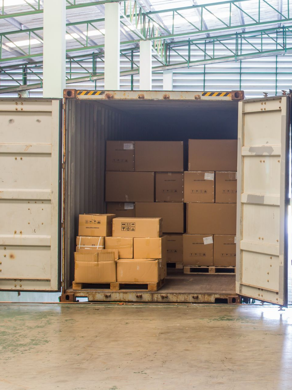 Conteneur ouvert rempli de cartons empilés dans une zone de chargement d'entrepôt