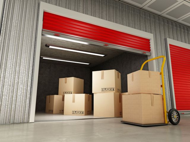 Pièce de stockage avec des cartons empilés sur un transpalette près d'une porte sectionnelle rouge
