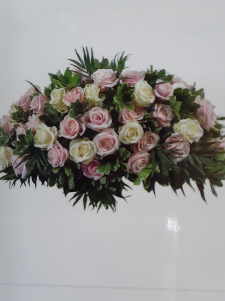 Un ramo de rosas rosas y blancas con hojas verdes.