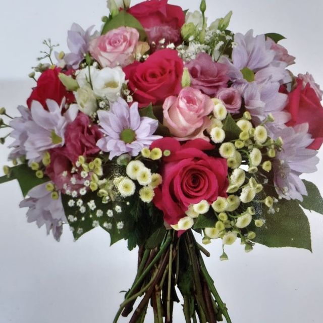 Un ramo de flores rosas y moradas con hojas verdes.