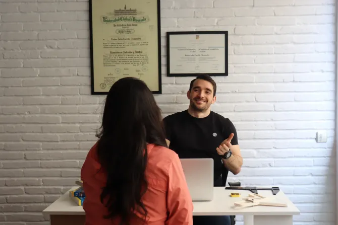 Una mujer frente a un hombre en un escritorio con una laptop