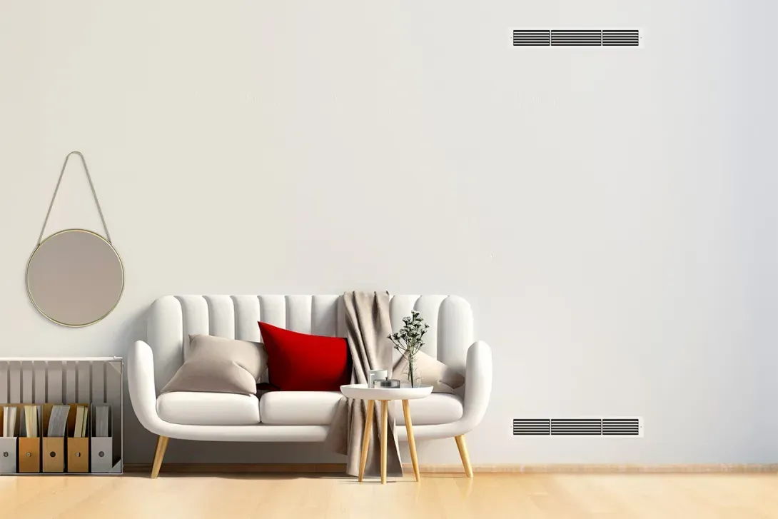 Salon avec canapé blanc, coussin rouge et éléments en bois sur un mur blanc.