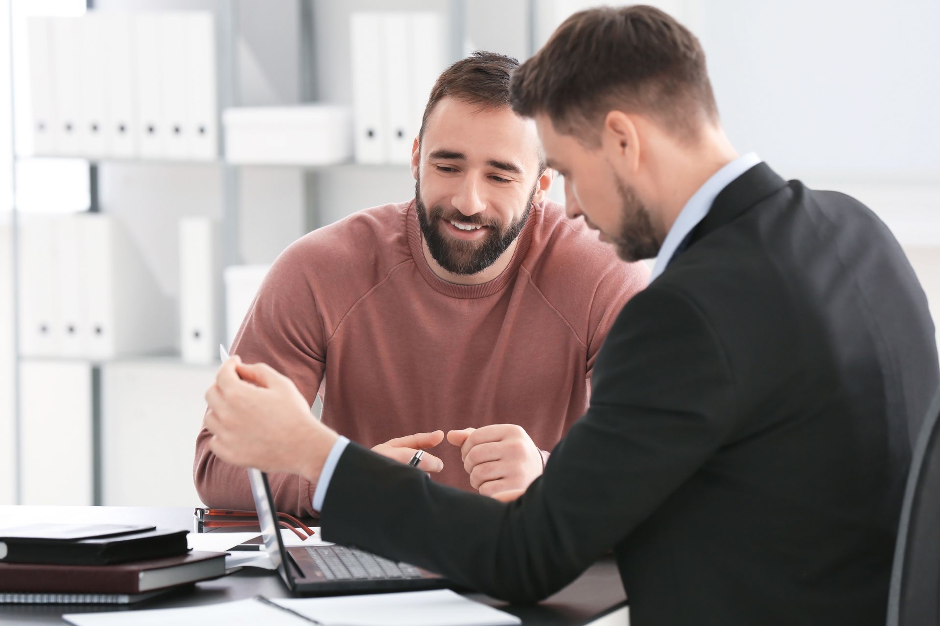 Deux hommes examinent des documents à un bureau, dans un environnement de bureau.