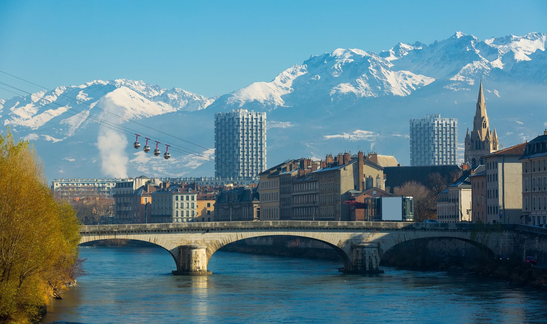 Pont sur la rivière, bâtiments de la ville, montagnes et téléphériques à Grenoble, en France.