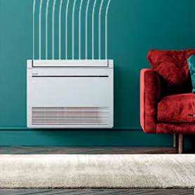 Unité de climatisation murale blanche avec bouches d'aération, à côté d'un canapé rouge contre un mur turquoise.