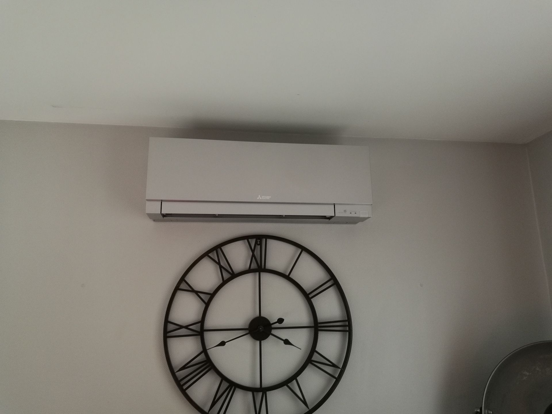Unité de climatisation au-dessus d'une grande horloge ronde fixée au mur.