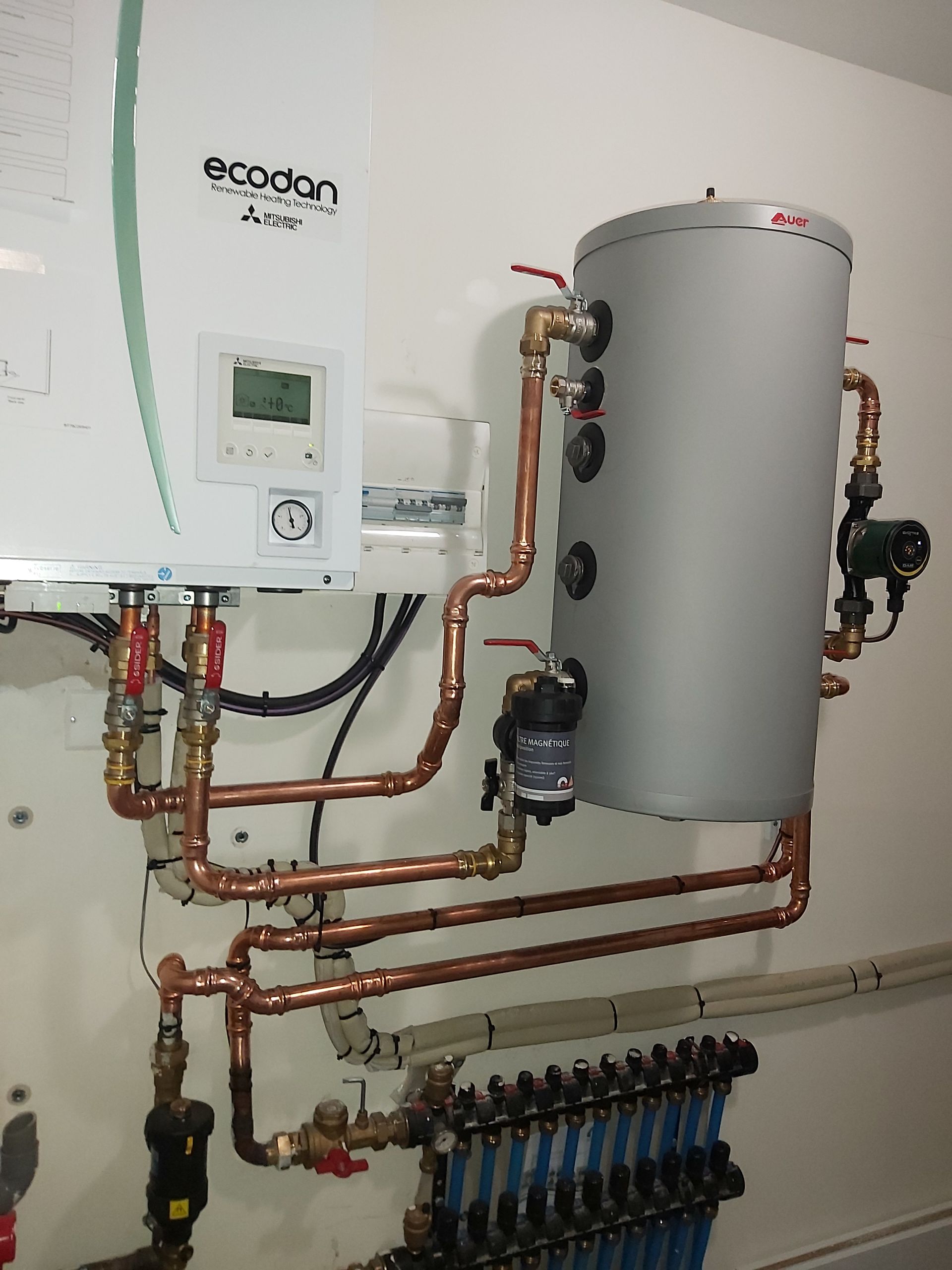 Mur blanc avec chaudière, tuyaux en cuivre, chauffe-eau et collecteur pour un système de chauffage.