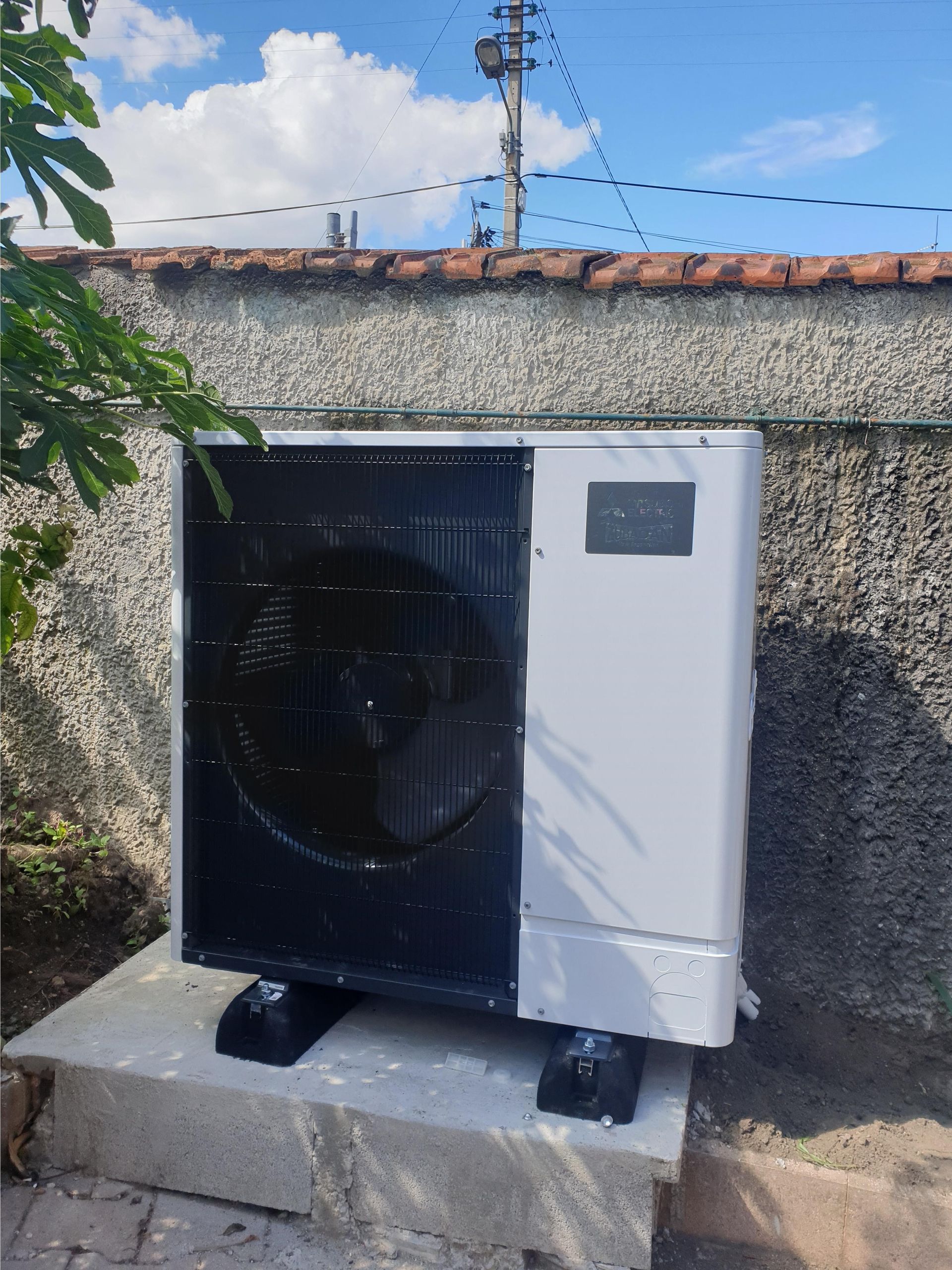 Unité de pompe à chaleur, noire et blanche, contre un mur texturé, montée sur une base en béton.