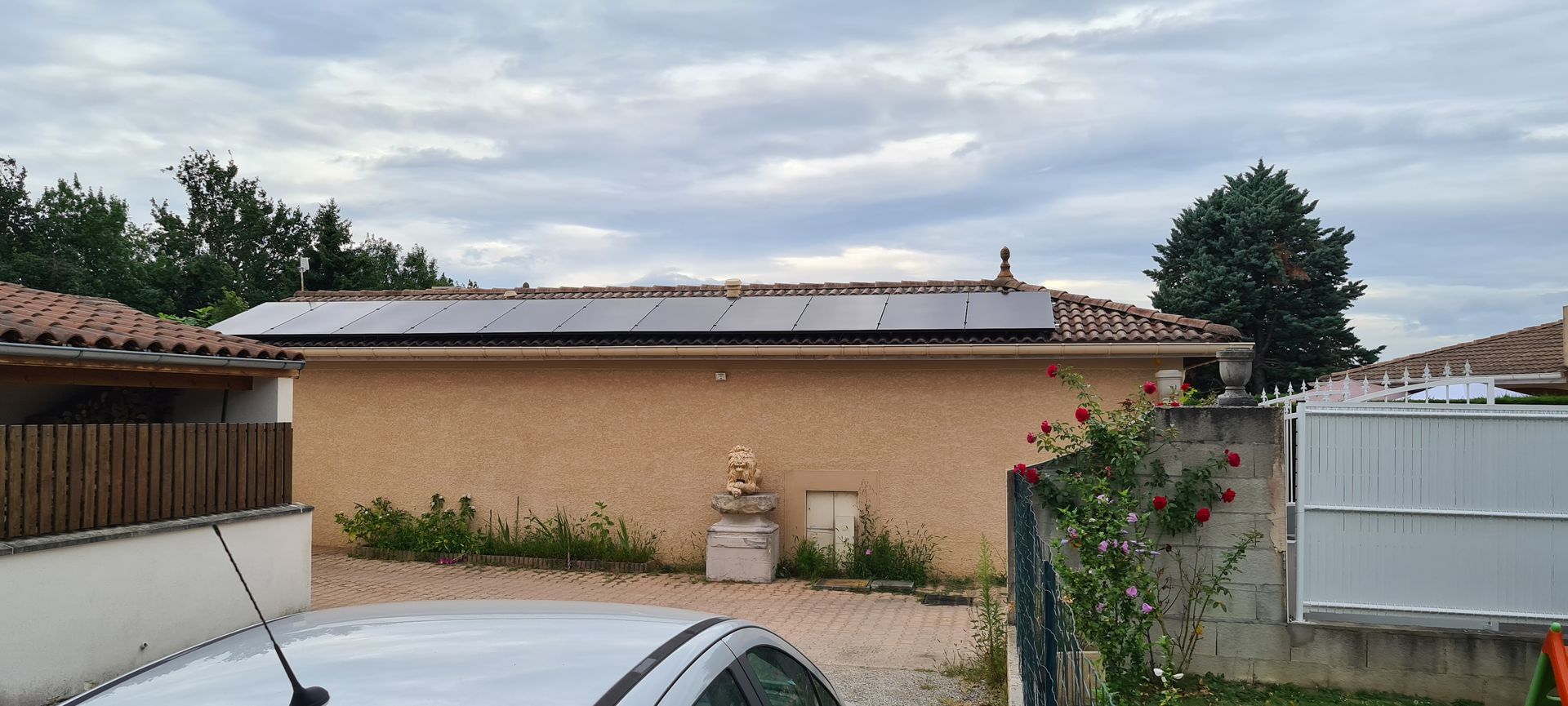 Une maison avec des panneaux solaires sur le toit, sous un ciel nuageux.