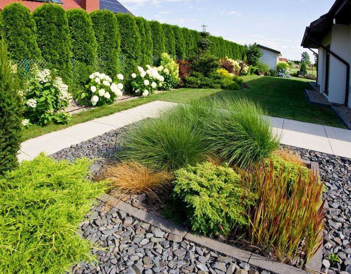 Un jardin avec des haies, des hortensias, des buissons et des allées