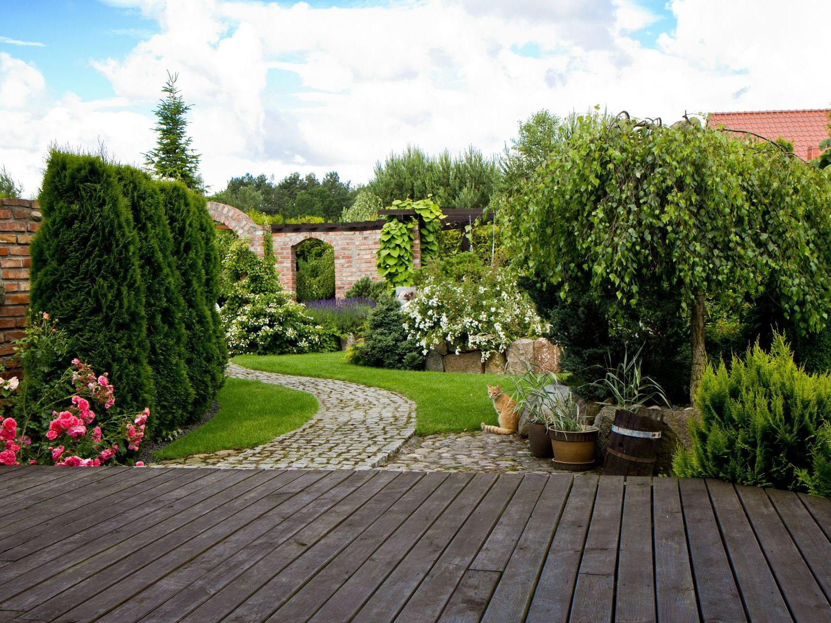 Jardin avec une allée et une terrasse en bois