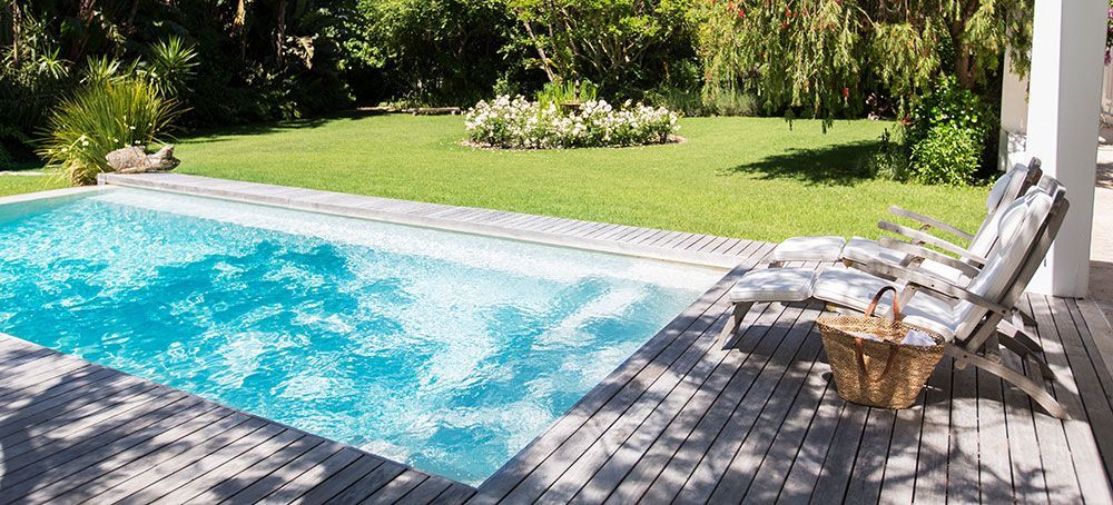 Piscine bordé par une terrasse et un jardin arboré