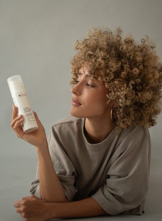 Frascos, caja e ingredientes (frutos secos) para el tratamiento con aceite de argán. Marrón y dorado.