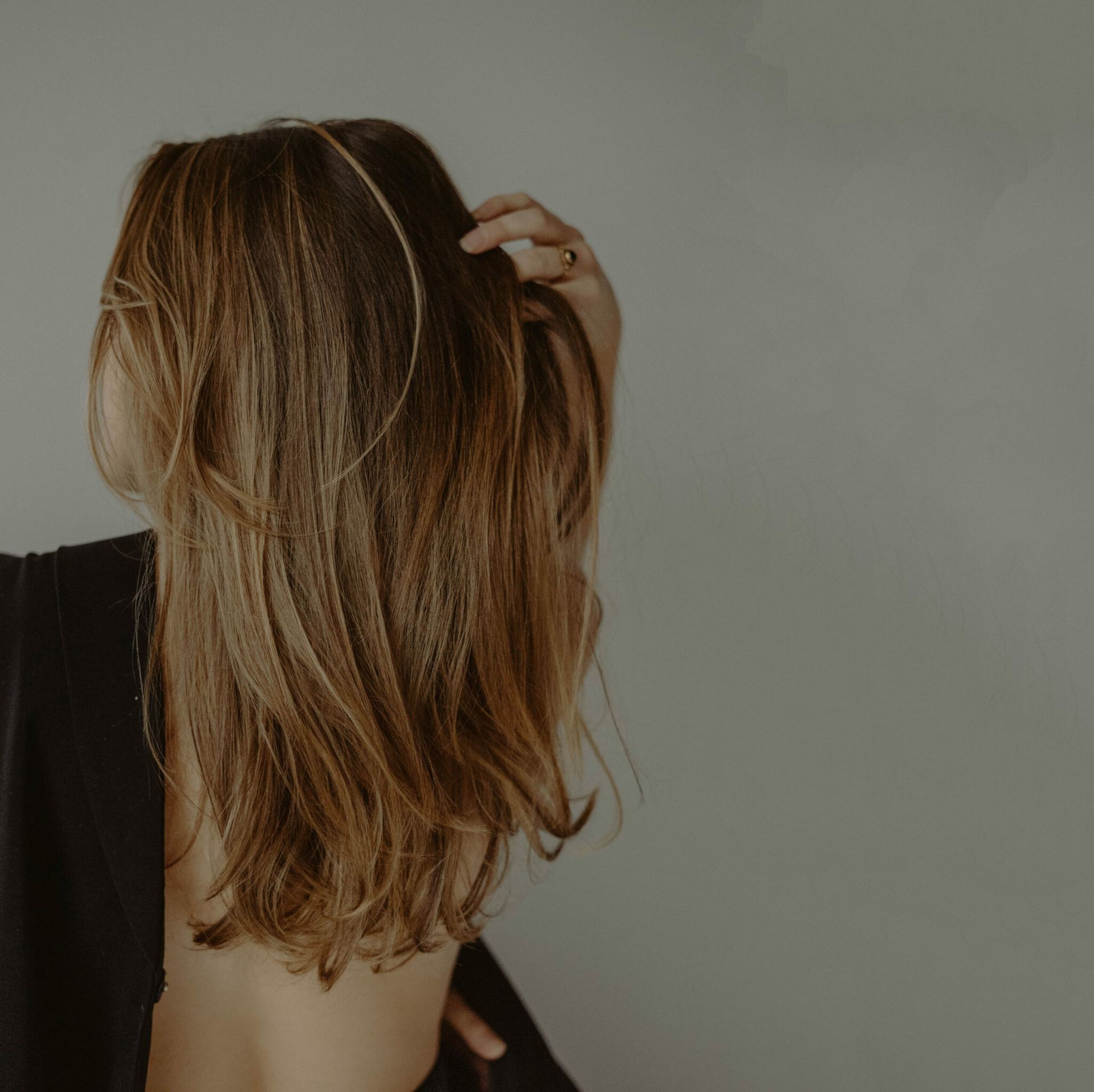 Mujer aplicándose crema hidratante en la cara, sonriendo sobre un fondo naranja.