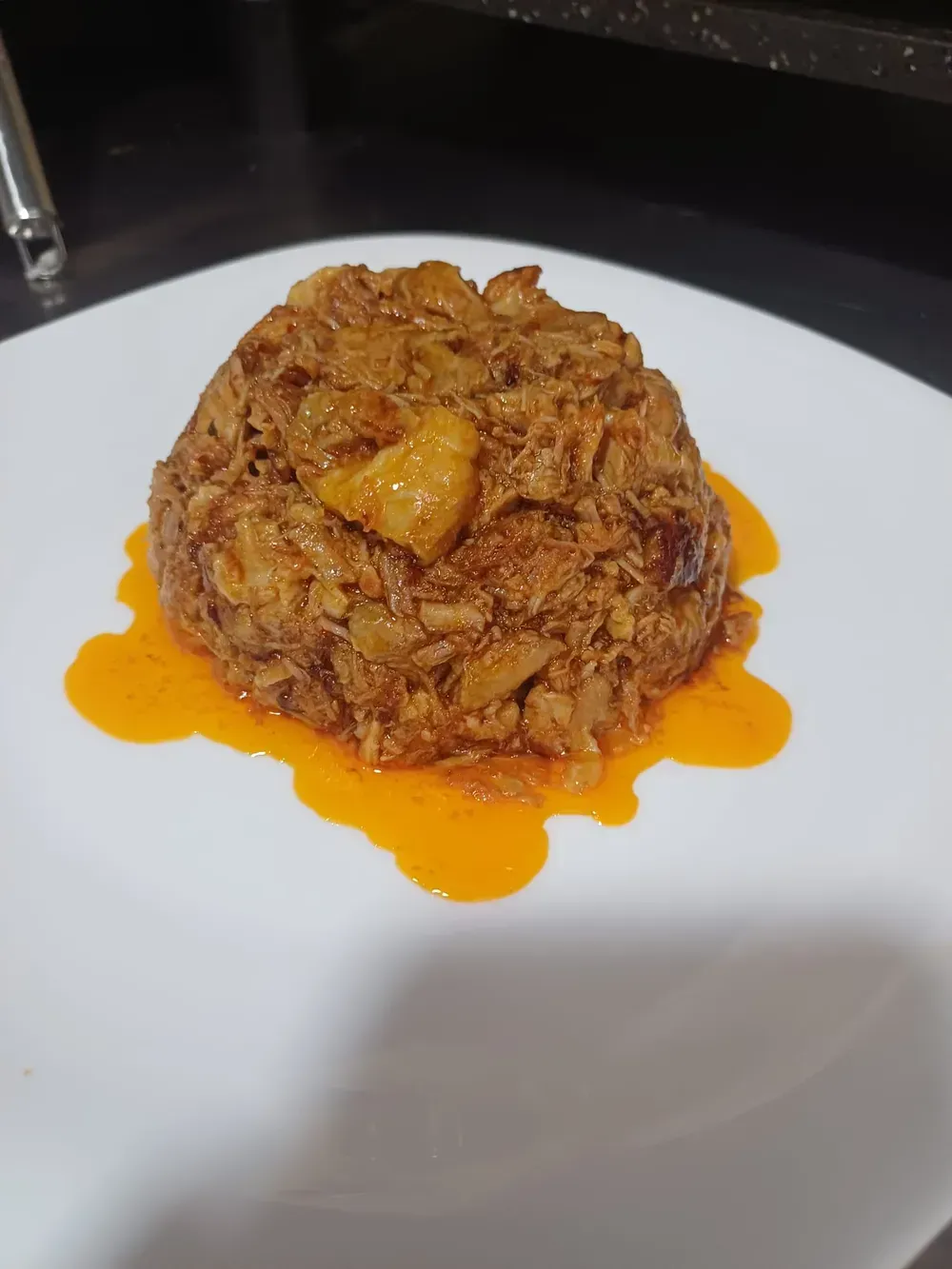 Plato sabroso de carne y verduras sobre salsa de naranja, presentado en plato blanco.