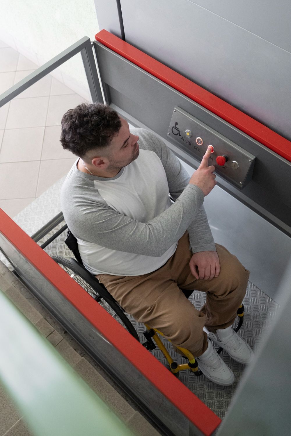 Un hombre en silla de ruedas está sentado en un ascensor y presiona un botón.