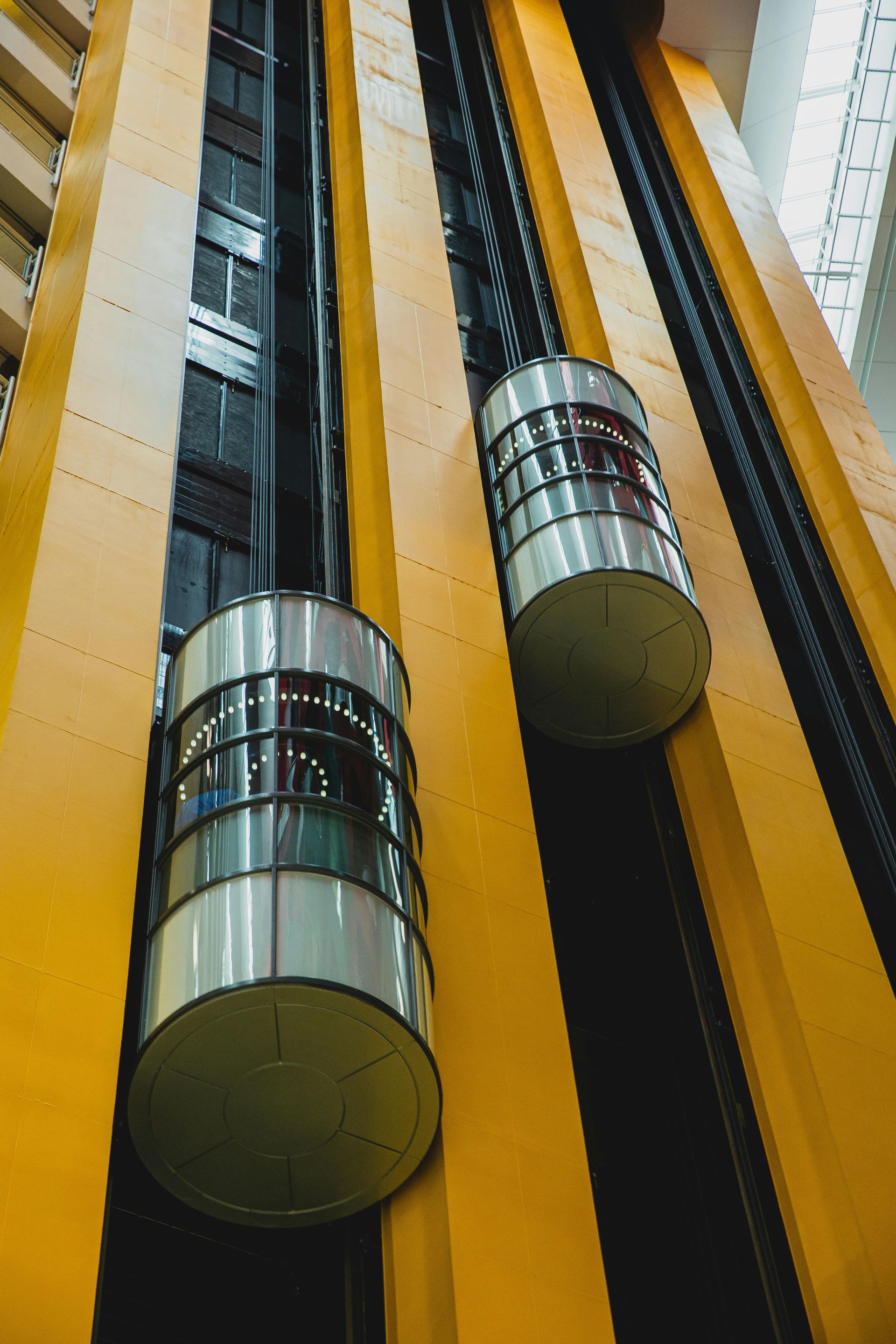 Dos ascensores suben por un edificio amarillo.
