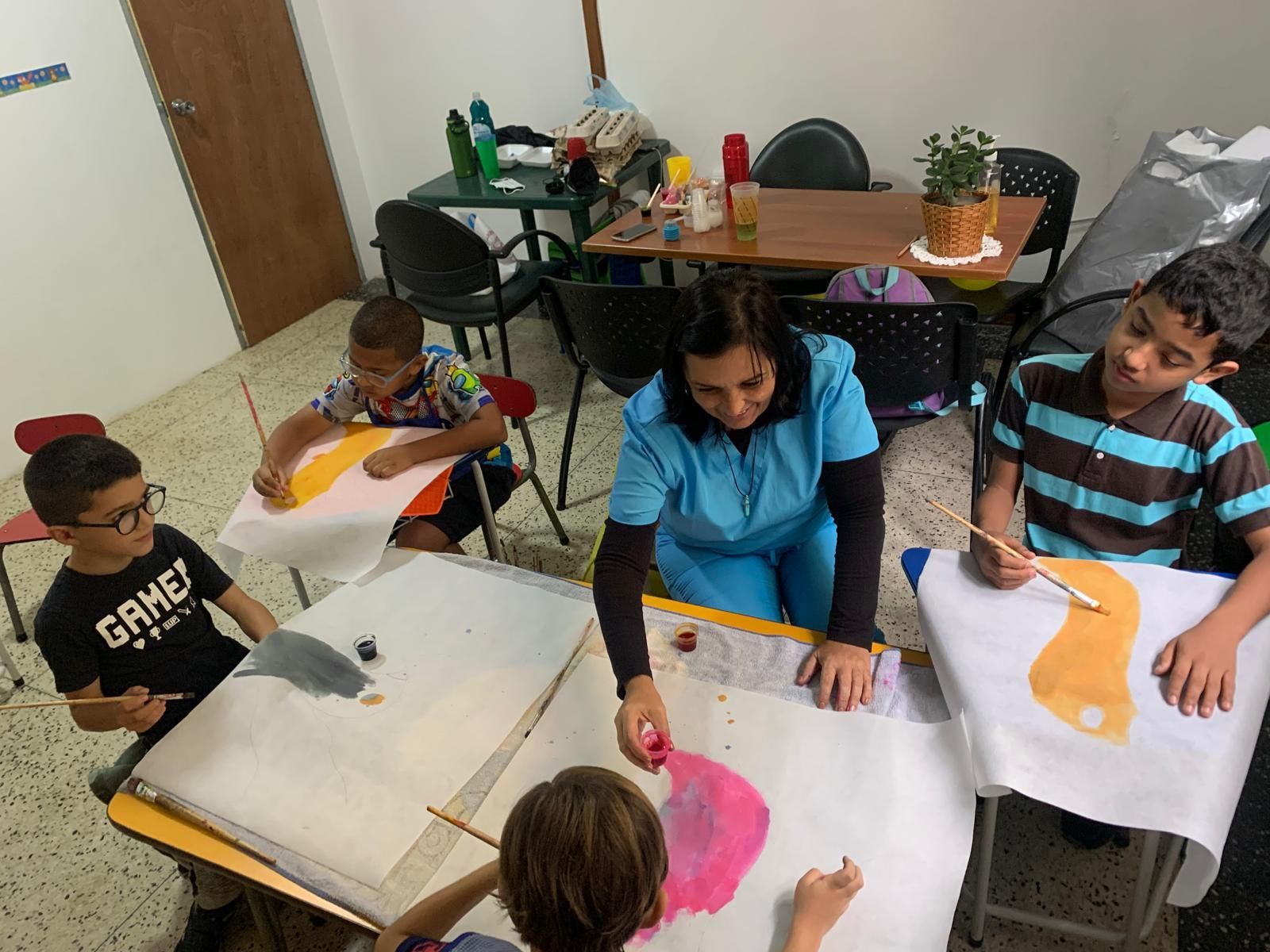 Niños y un instructor pintan símbolos Yin Yang en un aula.