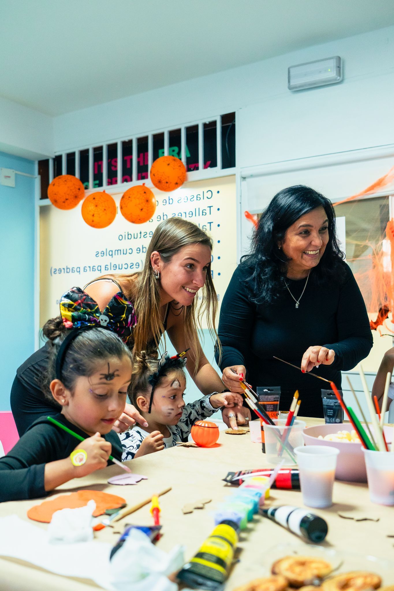 Un grupo de personas está sentada alrededor de una mesa pintando calabazas.
