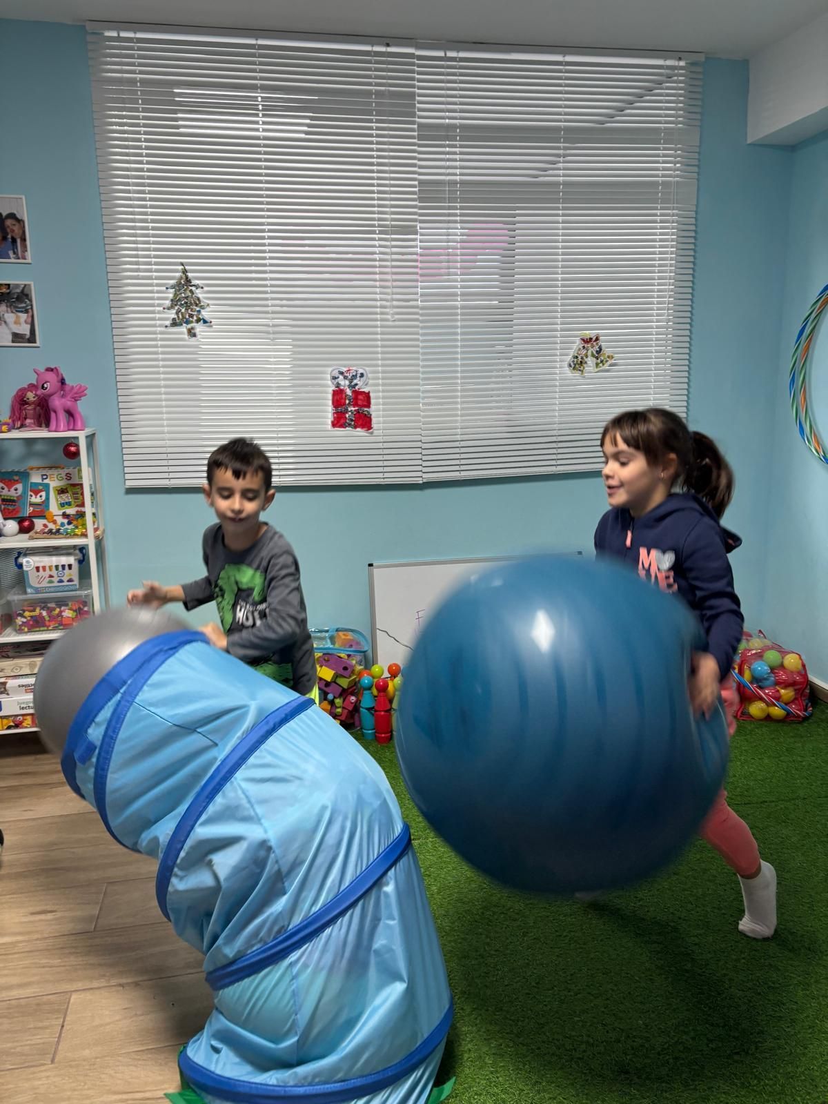 Un niño y una niña están jugando con pelotas en una habitación.
