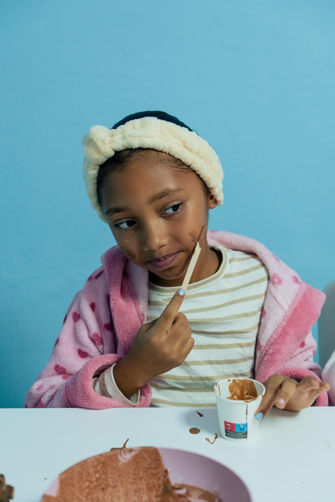 Una niña está sentada en una mesa comiendo helado.