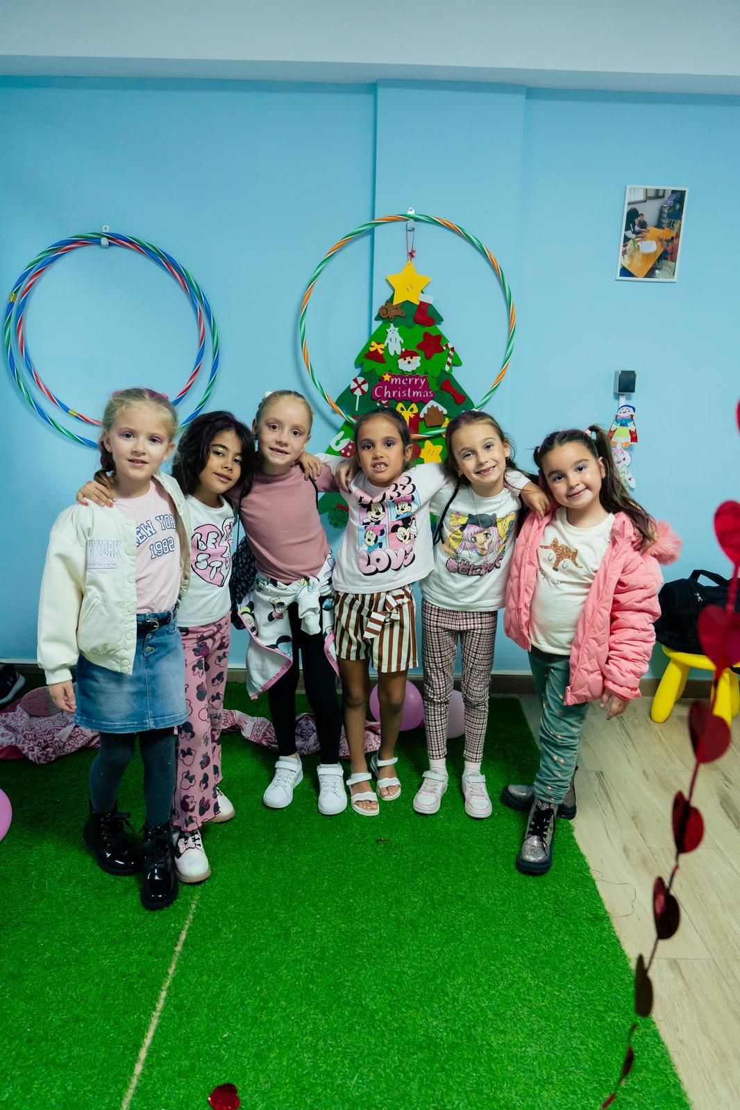 Un grupo de chicas jóvenes posan para una foto frente a un árbol de Navidad.